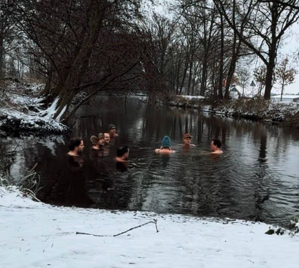 Serene tropical beach with calm blue waters, palm trees, and a distant small island under a partly cloudy sky.