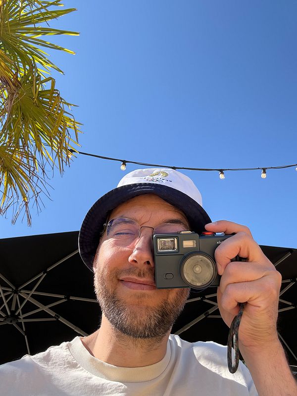 Close-up of a vintage-style screen-free digital camera with a film-winding mechanism and a soft-focus background.