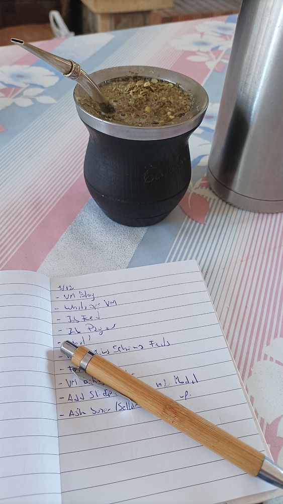 A cozy workspace featuring a traditional mate cup, a thermos, and a notepad with a to-do list.