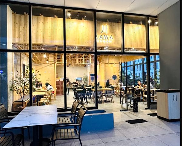 A modern Japanese restaurant named Kawa with a warm, inviting interior is visible through large glass windows.