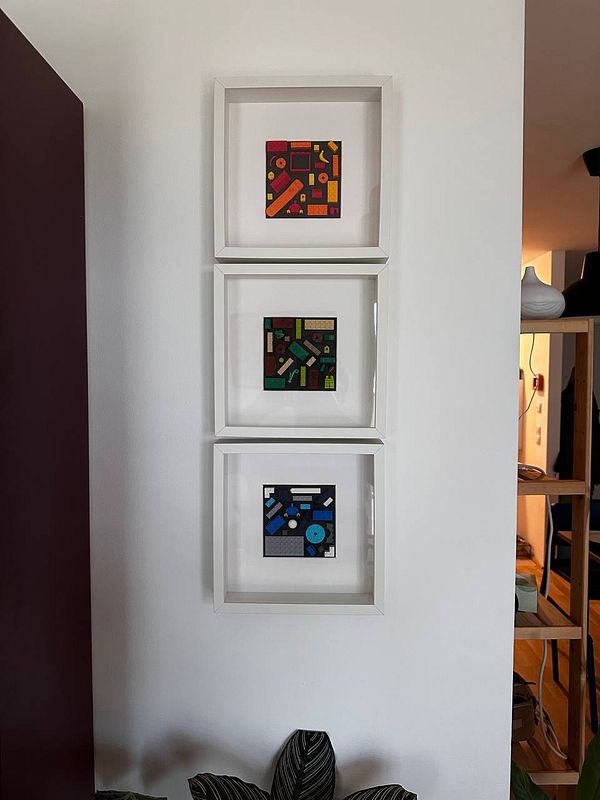Three framed abstract paintings are displayed on a wall.