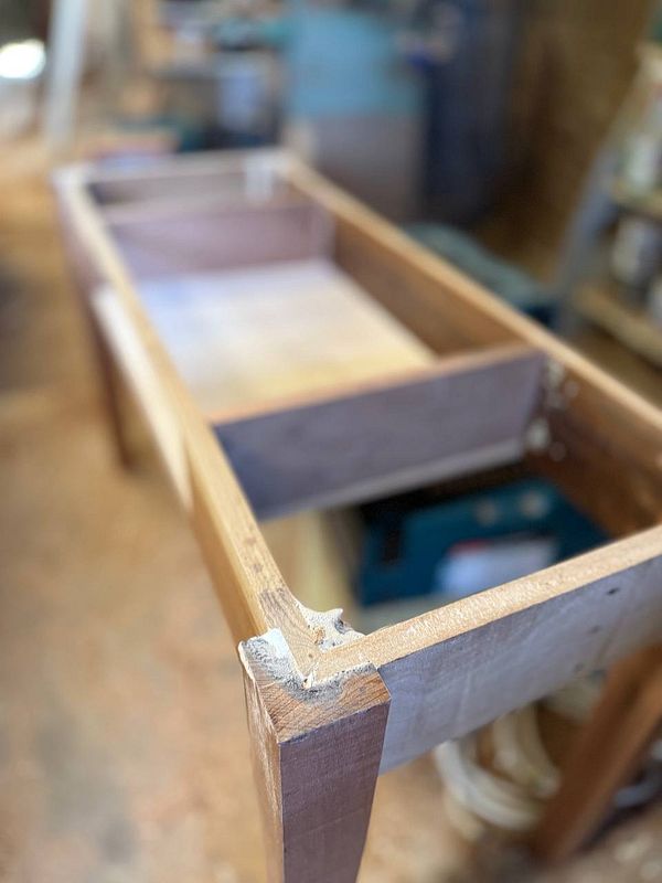 A partially constructed wooden table is shown in a workshop setting.