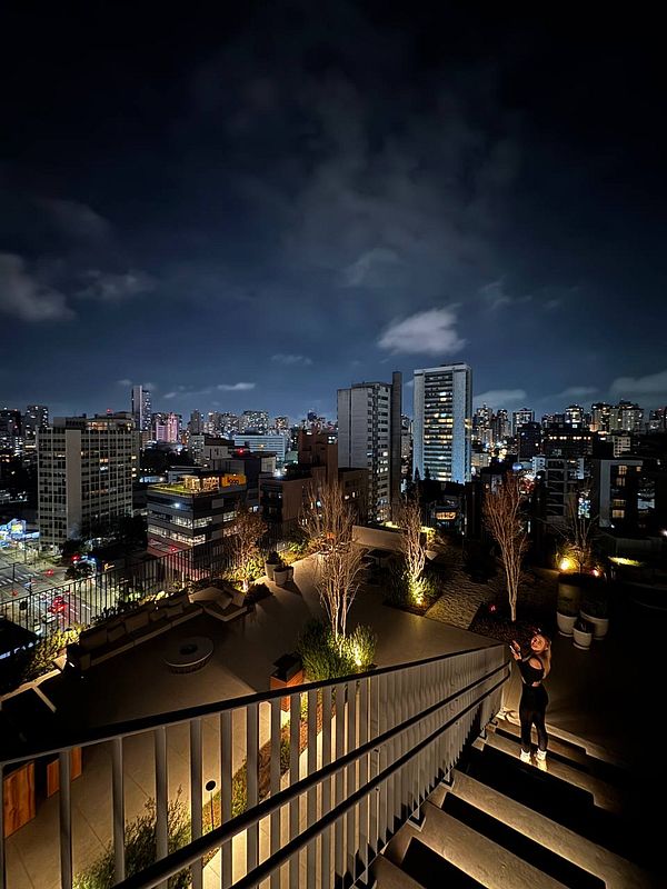 A nighttime view from a rooftop terrace overlooking a city skyline in Brazil.