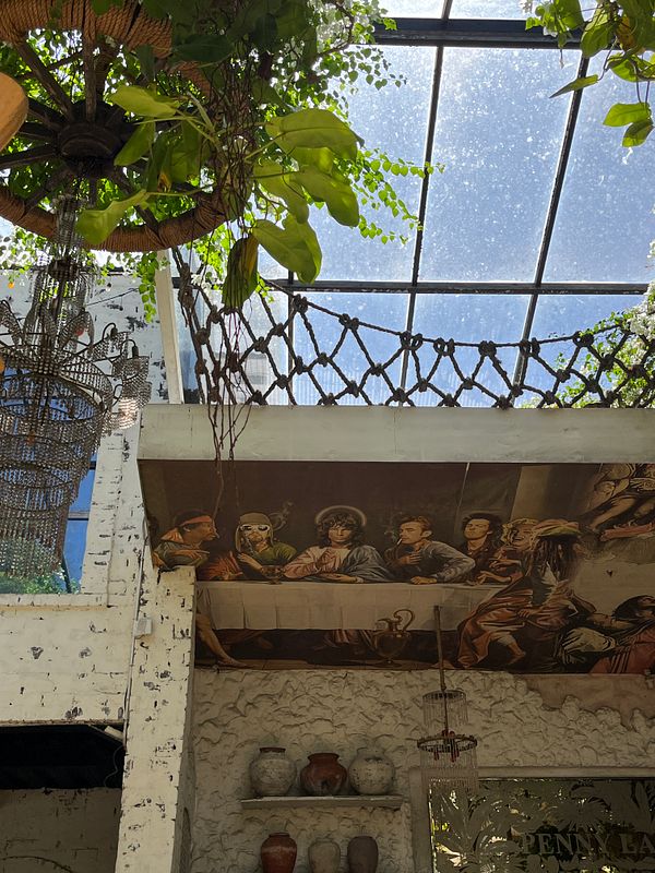 The image captures a vibrant indoor space featuring a ceiling adorned with plants and a mural depicting a historical scene.