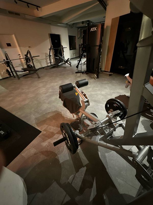 A dimly lit gym space featuring various workout equipment.