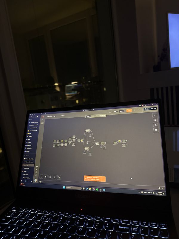 A laptop screen displays an n8n workflow interface in a dimly lit environment.
