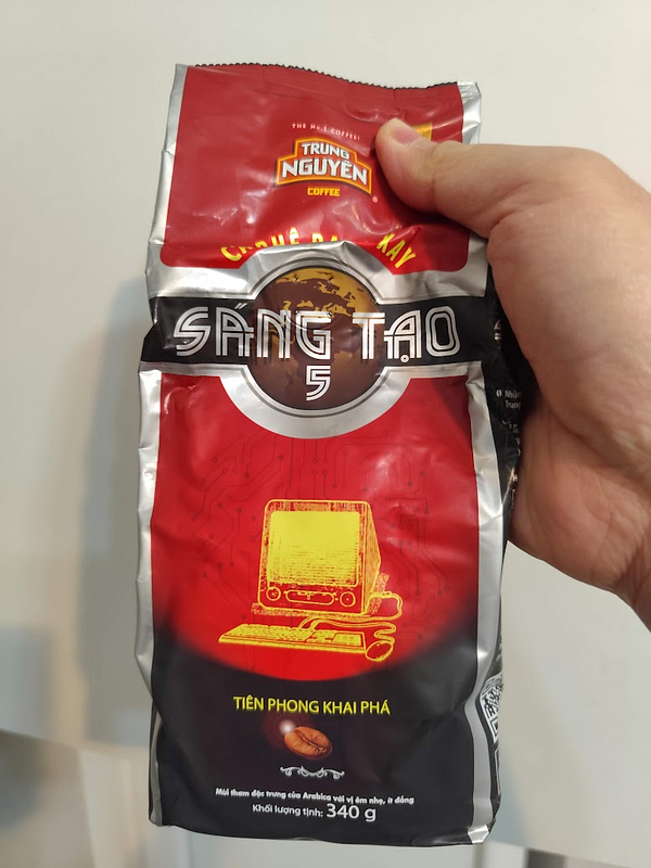 A hand holds a bag of Trung Nguyen coffee labeled 'Sáng Tạo 5'.