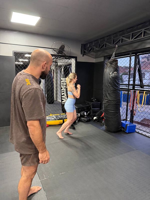 Photograph of a muscular man practicing Muay Thai in a gym environment.