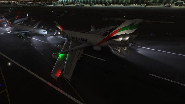 A nighttime view of multiple aircraft at Dubai International Airport, showcasing their illuminated features.
