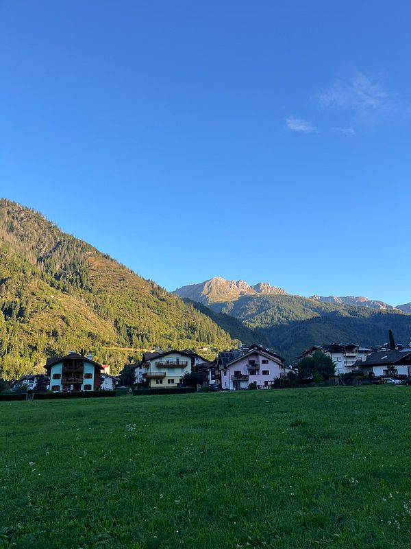 A picturesque mountain landscape with colorful houses in the foreground under a clear blue sky.