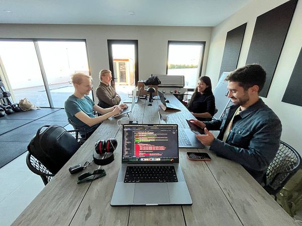 A group of four individuals is engaged in a coworking session at a modern workspace.