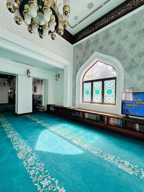 A serene interior view of a mosque featuring intricate design elements and a vibrant carpet.