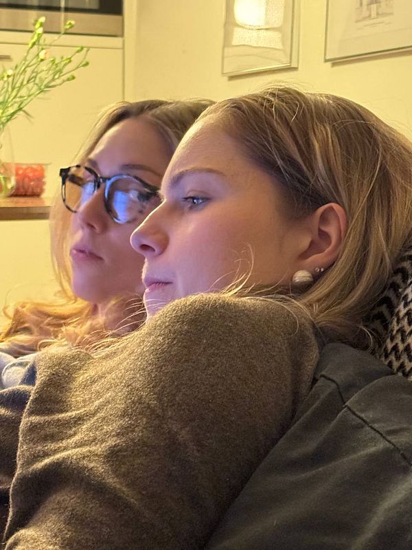 Two young women are focused on a screen while sitting closely together.