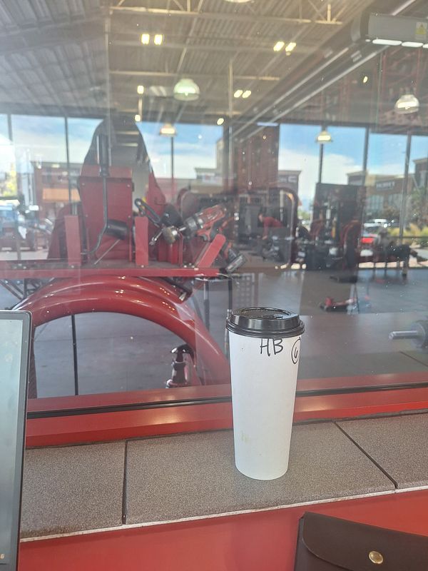 A coffee cup sits on a counter in a tire shop, with a view of the tire replacement area in the background.