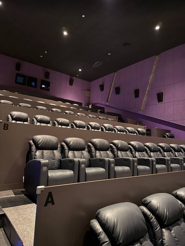 Interior view of a modern cinema theater in Korea with multiple rows of black leather reclining seats organized in sections labeled A, B, and C.