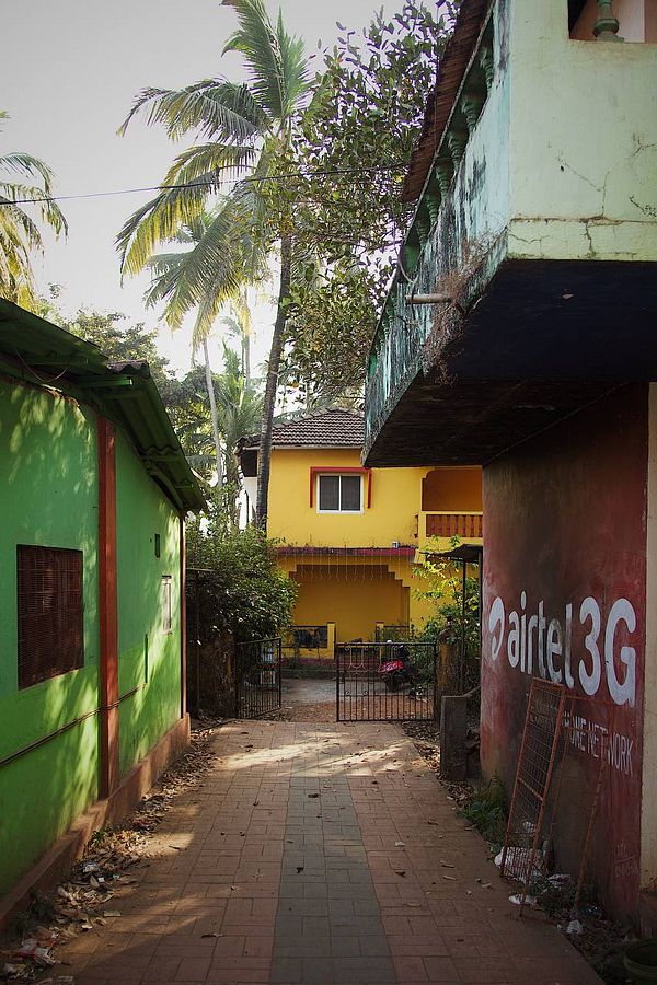 A vibrant alleyway in Goa featuring colorful buildings and palm trees.