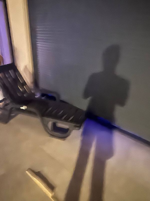 A shadow is cast on the floor next to a sunbed under electric blinds.