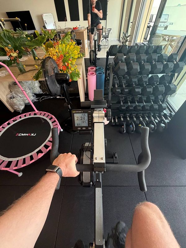 Overhead view of gym equipment including a barbell rack, a bench, and weight plates in a workout area.