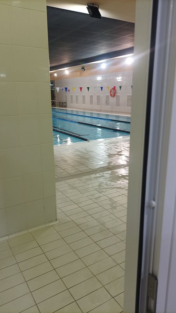 An indoor swimming pool is visible from a doorway, showcasing a clean and well-lit environment.
