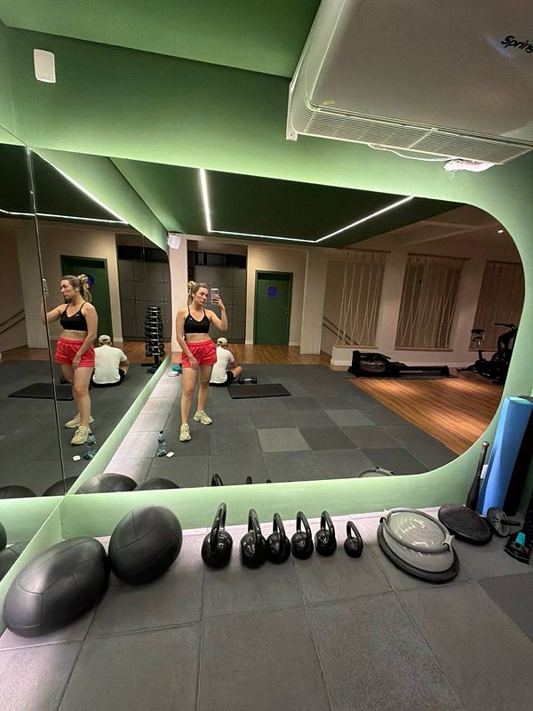 A man lifting weights in a gym environment with various equipment around.