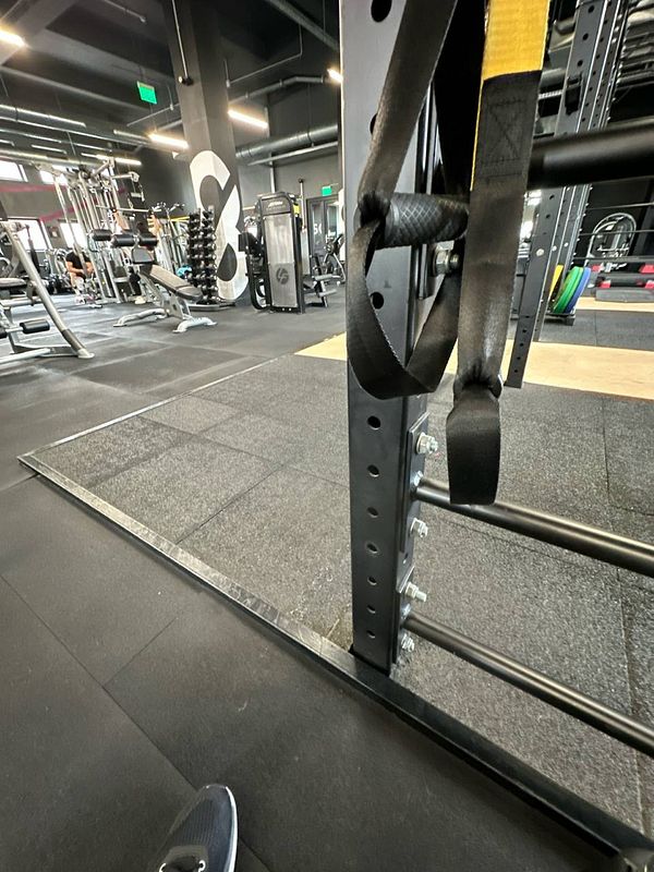 The image captures a corner of a modern gym featuring various workout equipment.
