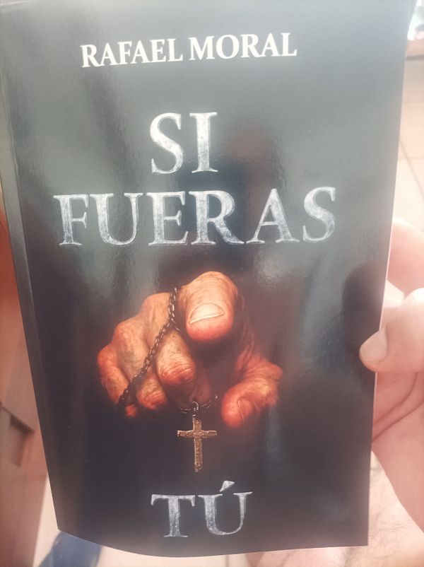 A hand holding a rosary with a cross is prominently featured on the cover of a book titled 'Si Fueras Tú' by Rafael Moral.