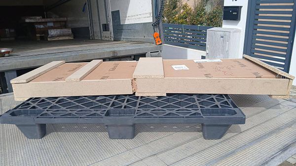 A damaged wooden table with visible cracks and broken legs lying on a wooden floor.