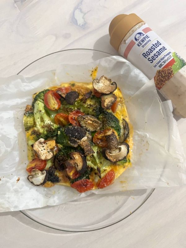 A colorful air-fried vegetable dish is presented on a plate with a bottle of roasted sesame dressing nearby.