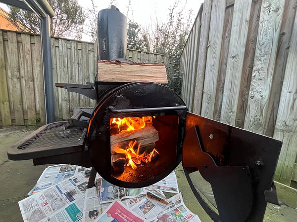 A smoker BBQ is being restored, with flames visible inside the firebox.