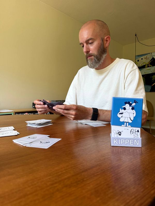Person playing a card game with colorful cards spread over a red table cloth.