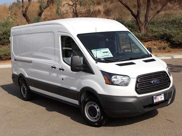 A white Ford van is parked on a paved surface, showcasing its spacious design.