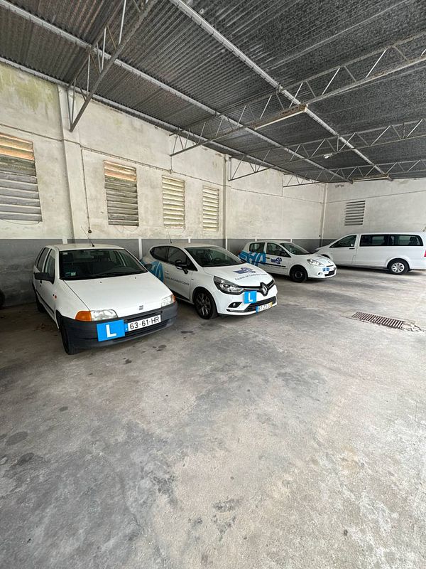 A parking area with several cars, including driving school vehicles marked with learner plates.
