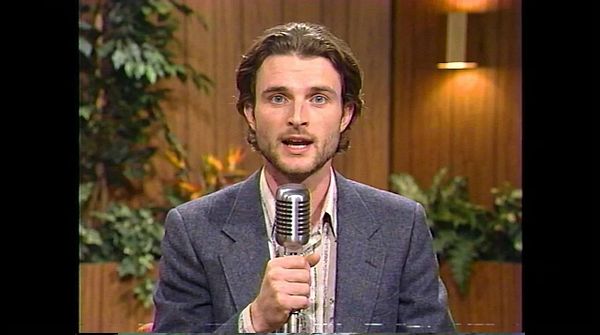 A colorful television shopping show still featuring two presenters and various displayed products.