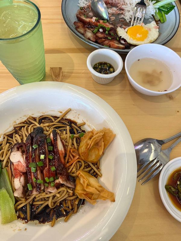 A delicious meal featuring noodles, roasted meat, and a variety of side dishes.