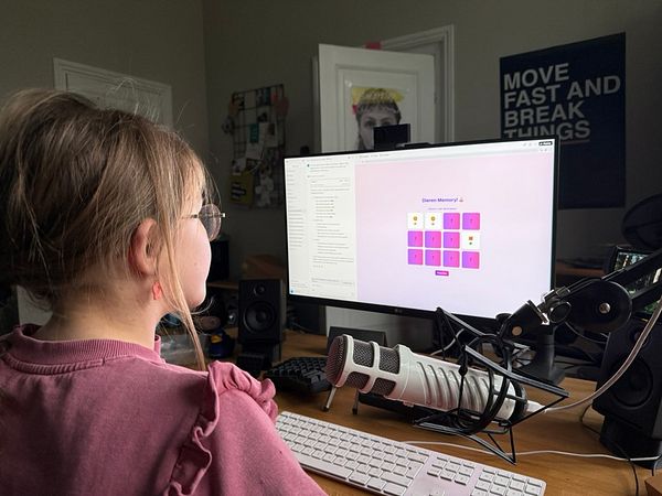 A child is programming a memory game on a computer while sitting at a desk.