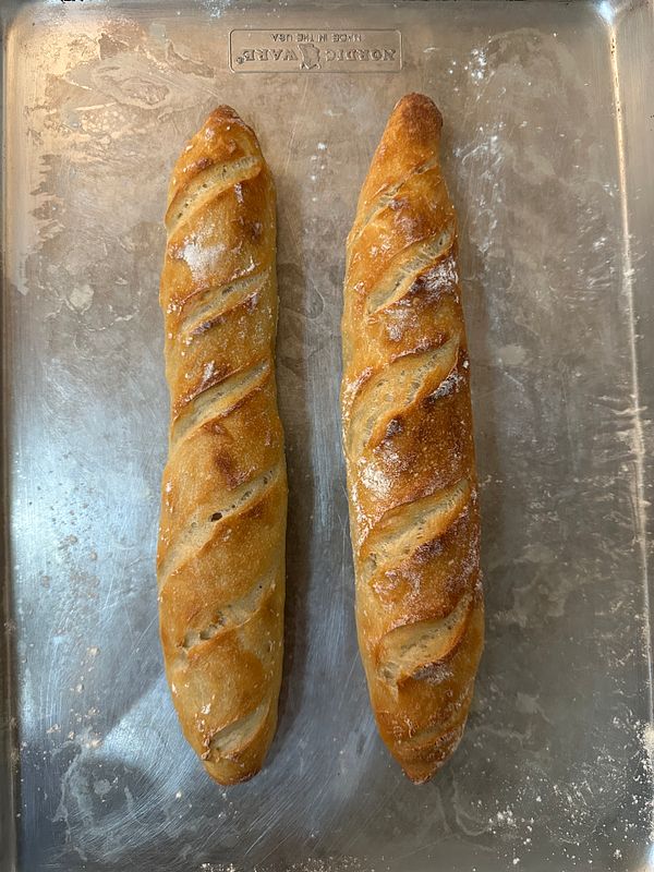 Close-up of two golden baguettes on a red surface.