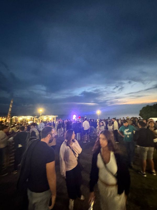 A lively outdoor festival scene at dusk with a crowd enjoying the Beerceira festival.