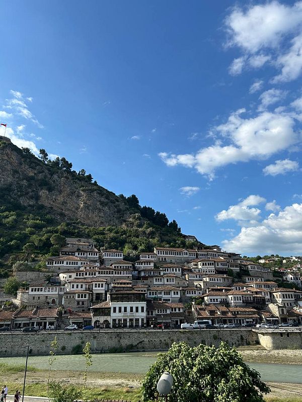 A picturesque view of an Ottoman-style village nestled on a hillside beside a river.