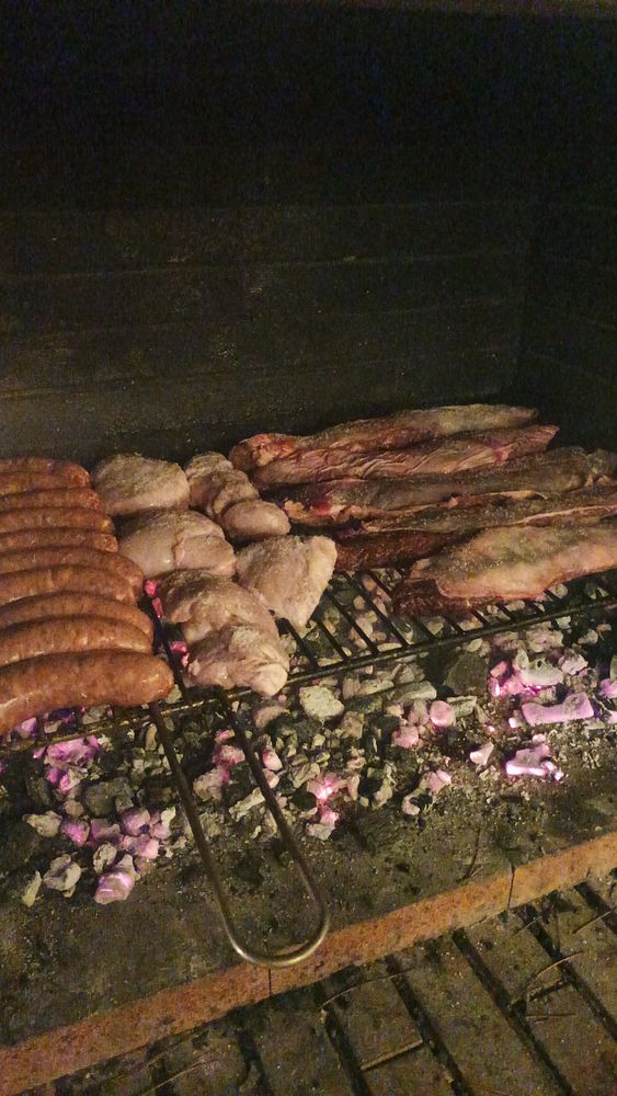 A grill filled with various meats cooking over glowing coals.