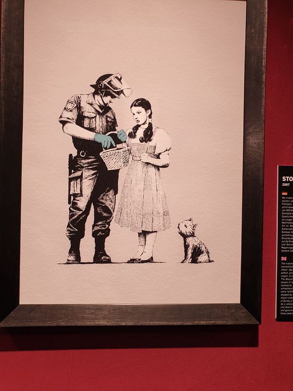 A Banksy artwork depicting a police officer interacting with a young girl and a dog.