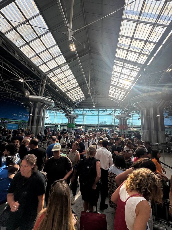 A crowded scene at Lisbon Airport showing a long queue for immigration.