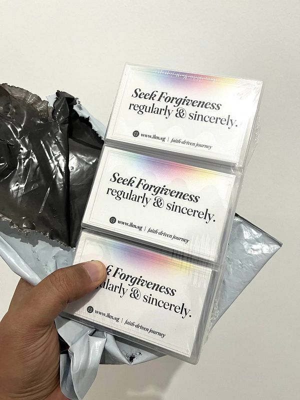 A hand holds three cards with a motivational message, alongside a partially opened package.