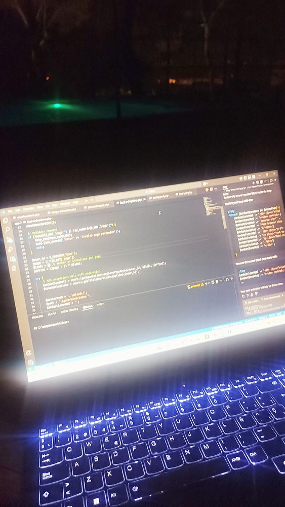 A laptop displaying code is positioned near a pool at night, illuminated by the screen's light.