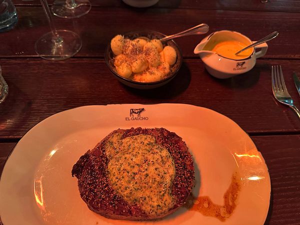 A beautifully plated steak de pimienta with sides on a wooden table.
