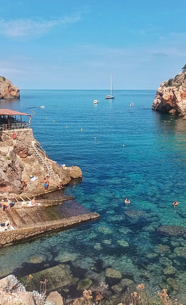 A picturesque coastal scene featuring clear blue waters and people enjoying the beach.