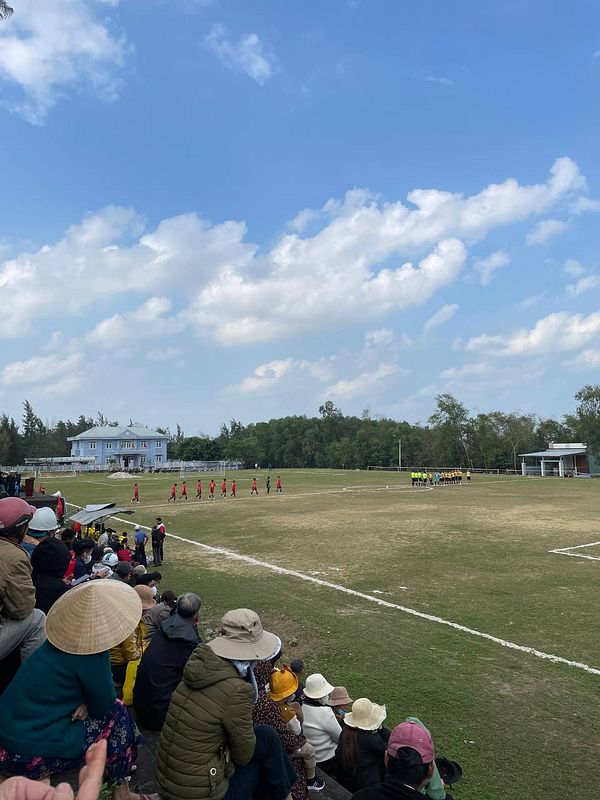 A lively scene of a local football match in a village setting.