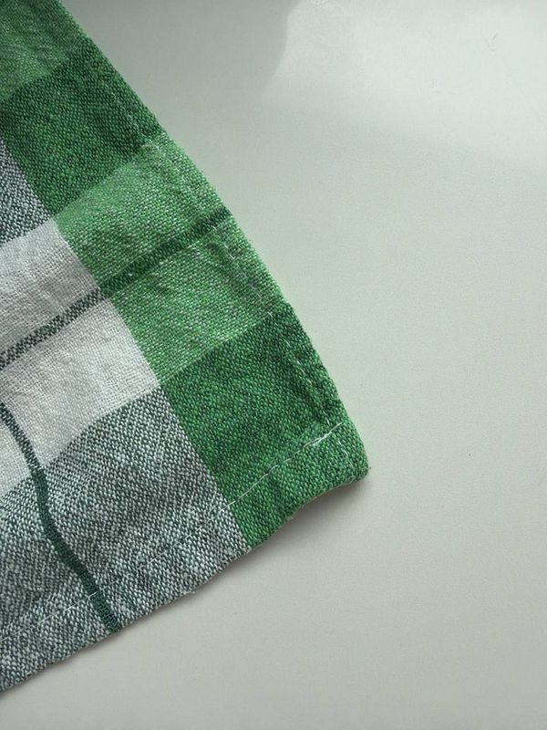 A close-up of a green and white checkered fabric corner on a smooth surface.
