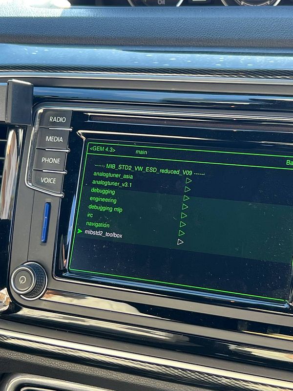 Close-up of a Volkswagen car infotainment system screen displaying the GEM 4.3 engineering menu with options including mibstd2_toolbox, debugging, and navigation.