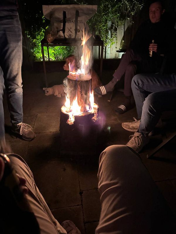 A cozy campfire gathering with friends in a dimly lit outdoor setting.