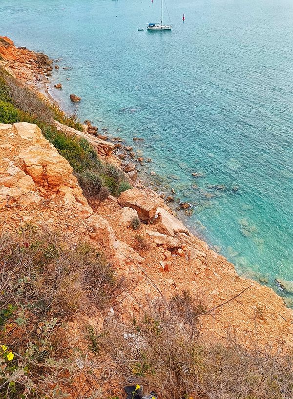 A scenic coastal view featuring rocky cliffs and a calm turquoise sea.